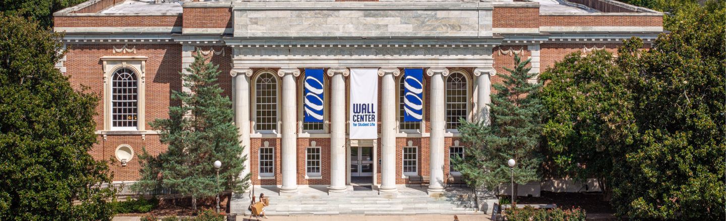 A brick building with ionic columns and banners that say 100 and Wall Center.