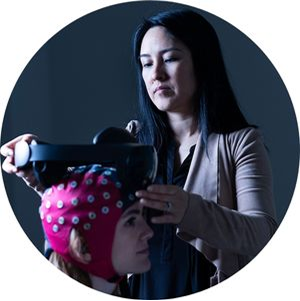Nanthia Suthana adjusting a headset on a person with a pink cover on their head.