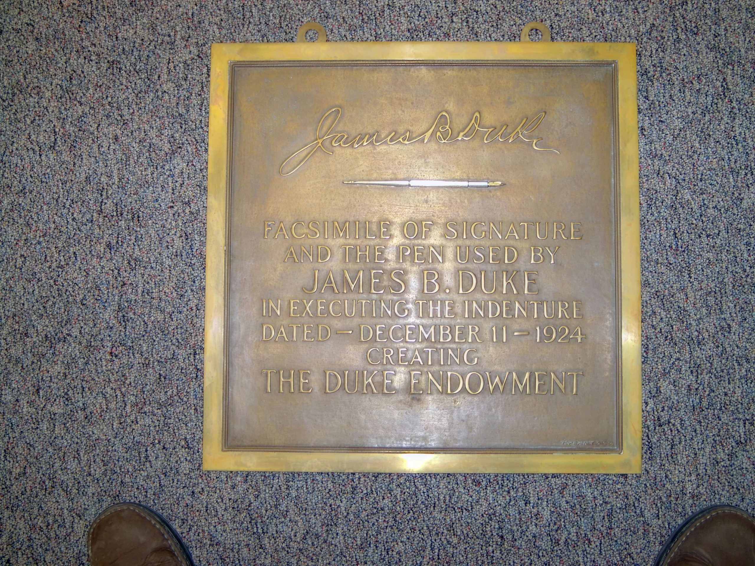 A bronze plaque with James B Duke's signature on it and a statement that says Facsimile of Signature and the pen used by James B. Duke in executing the indenture dated December 11, 1924 creating the Duke Endowment.