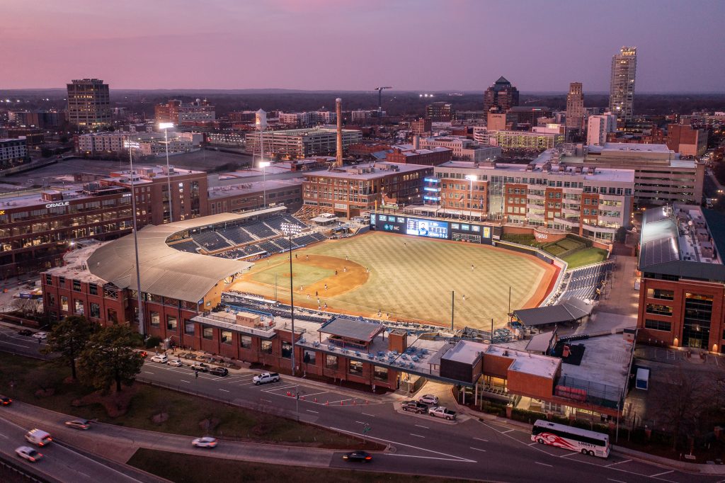 Aerial view of the Durham Bulls ballpark at night with the field lit up.