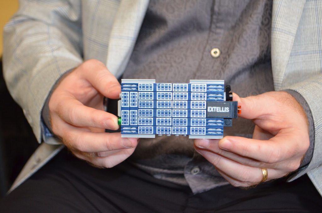 Extended fingers grasp a small containers that contain metamaterial satellite antennas