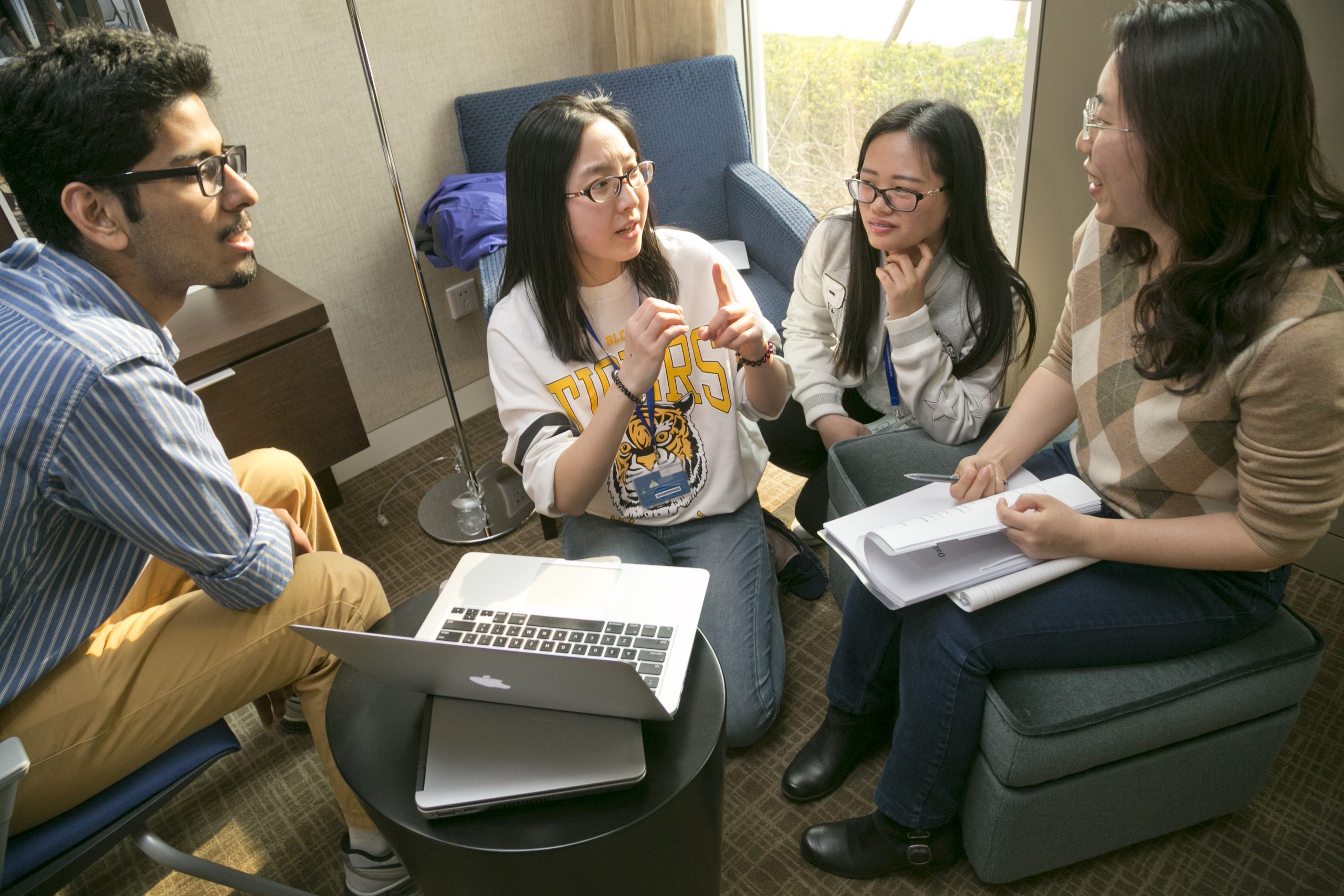 Four students sitting around a laptop in a lounge at DKU