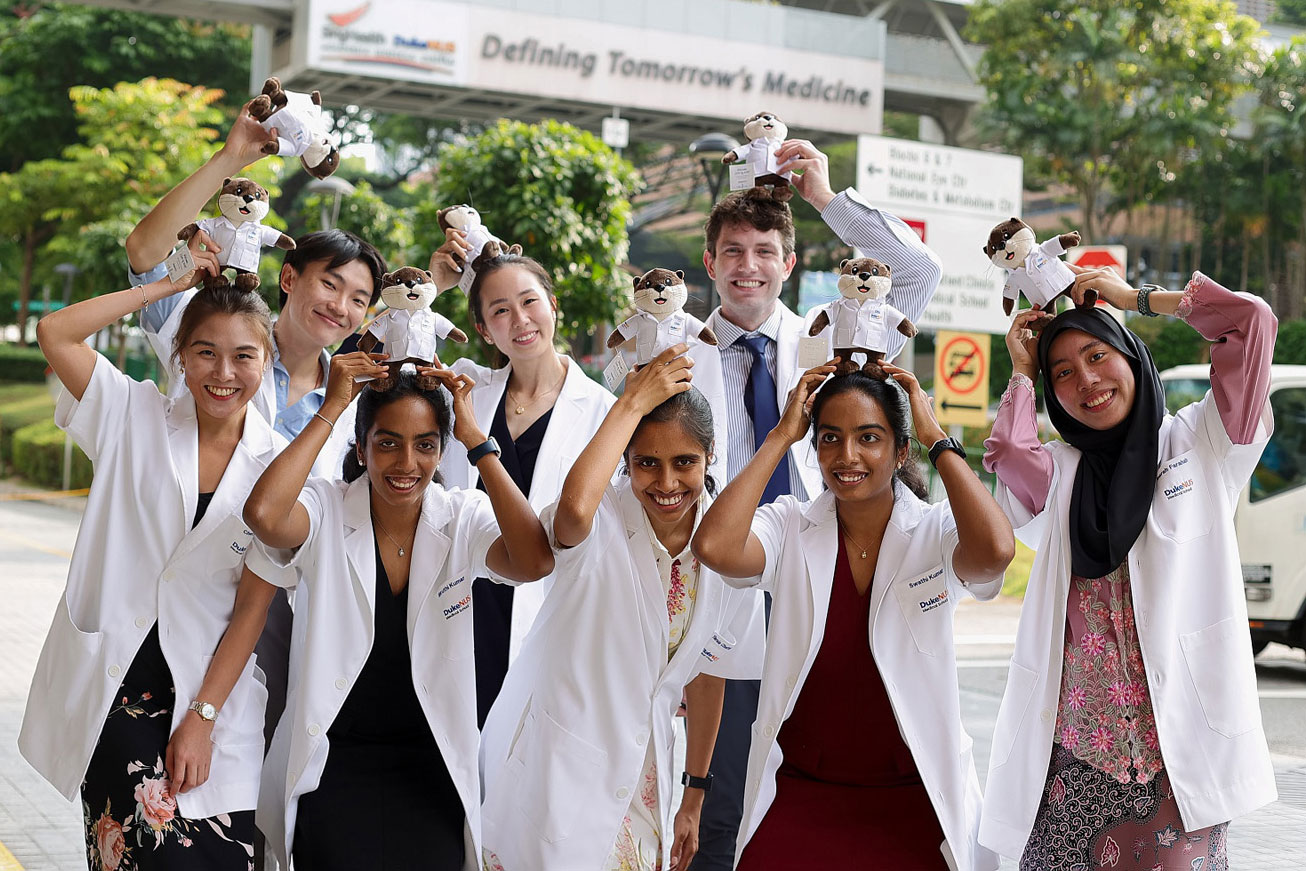 Duke NUS students pose for a photo outside with stuffed animals  on their heads