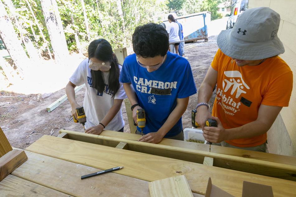 Duke students volunteering with Habitat for Humanity, using power drills to build a wooden structure.