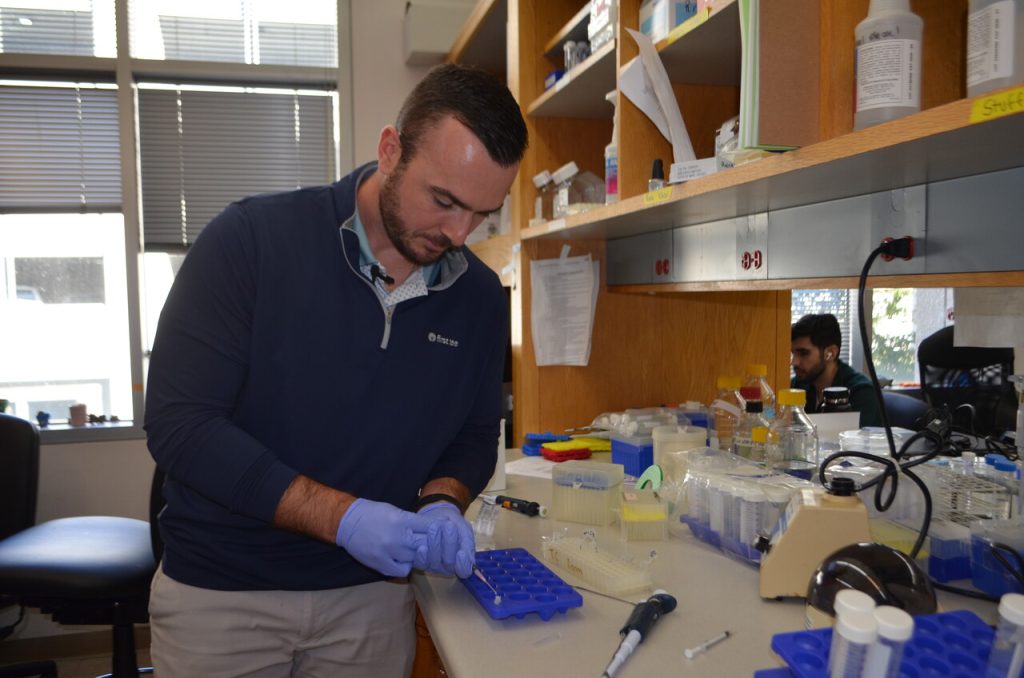 Man wearing blue-colored latex gloves while working in a lab