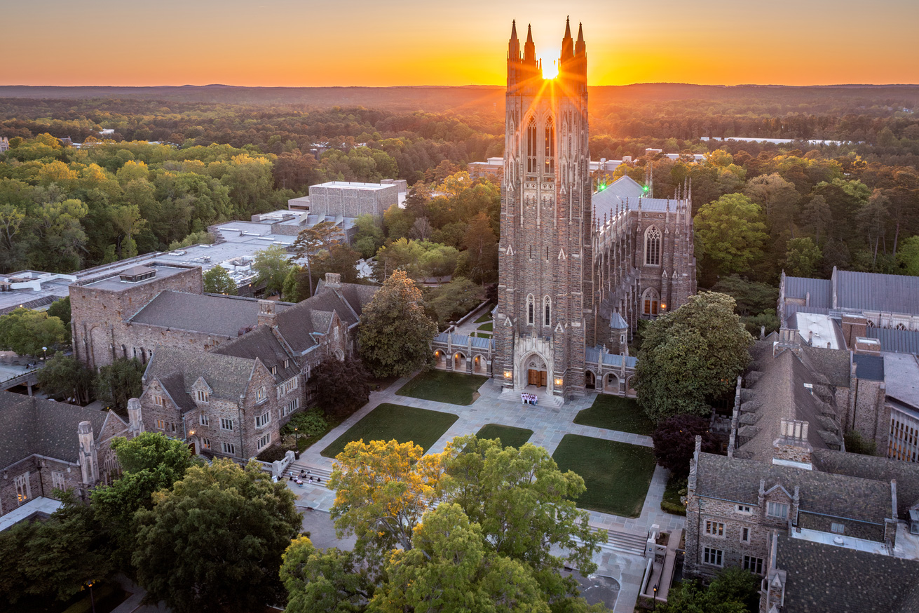An aerial of Duke chapel at sunrise with the quad in the foreground and the sun between the spires